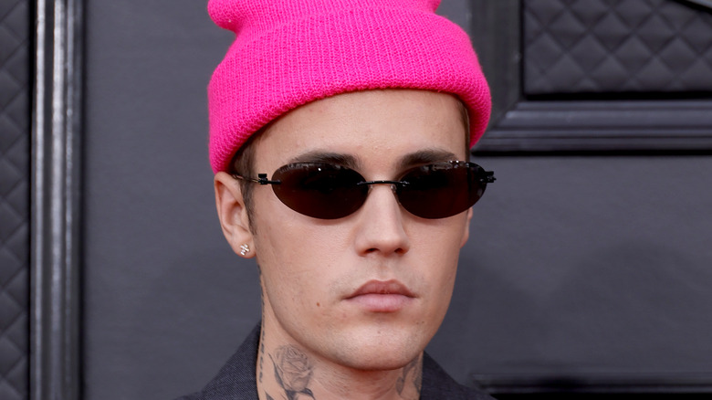 Justin Bieber wearing sunglasses and pink beanie