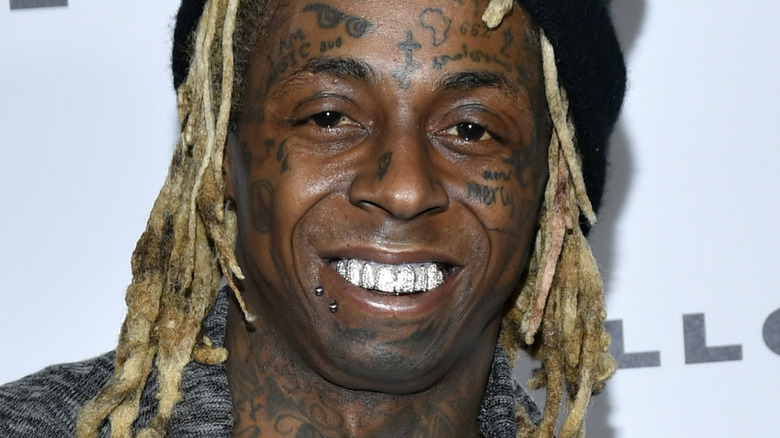 Lil Wayne wearing a black hat and gray coat