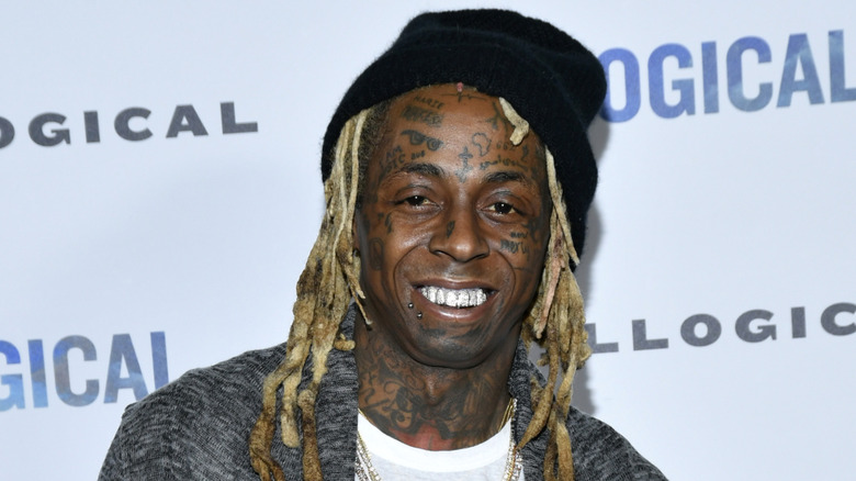 Lil Wayne wearing a black hat and gray coat