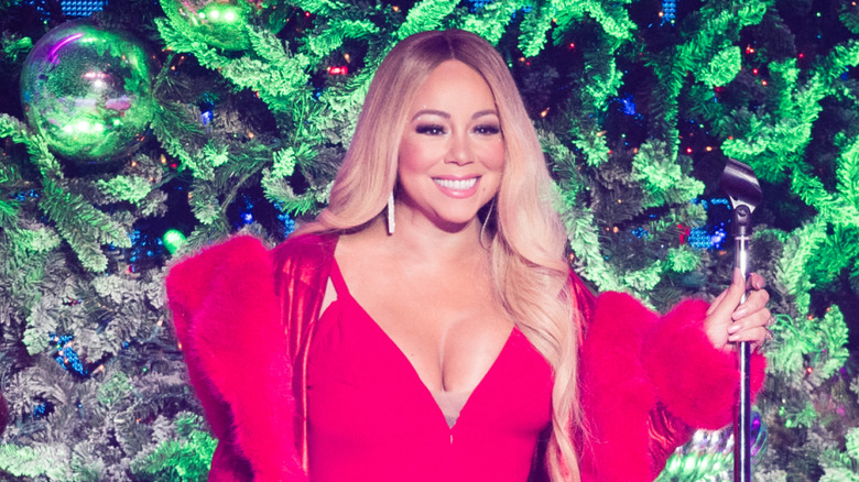 Mariah Carey singing in a red dress in front of a tree