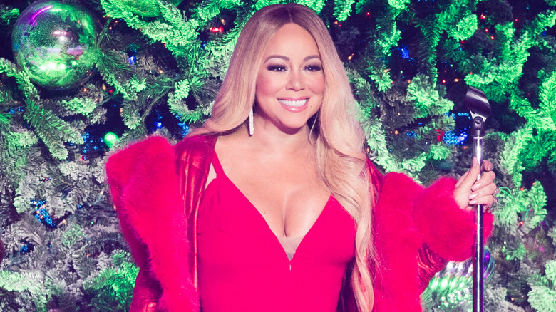 Mariah Carey singing in a red dress in front of a tree