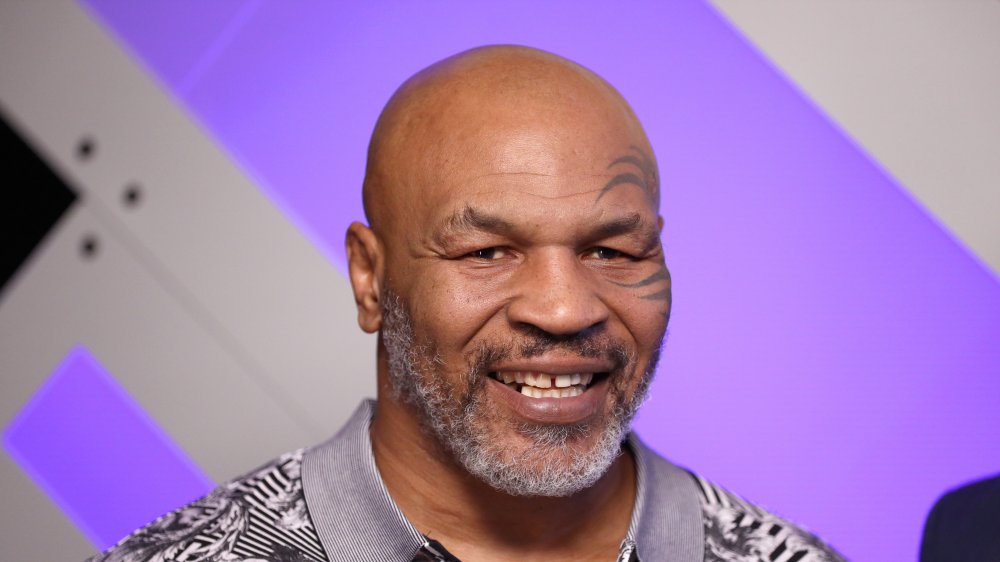 Mike Tyson smiling in front of purple wall