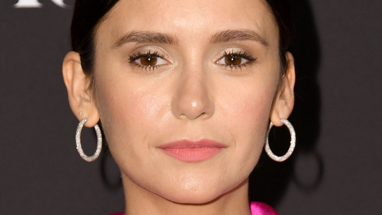 Nina Dobrev wears hoop earrings and a hot pink blazer