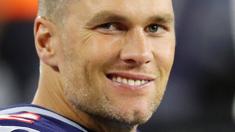 Tom Brady smiles at a football game