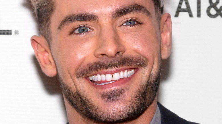 Zac Efron smiles with blonde hair