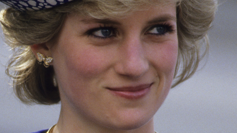 Princess Diana poses in royal blue outfit and beret.