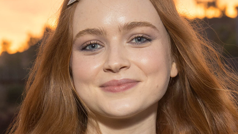 Sadie Sink smiles at camera with Prada barrettes in hair 