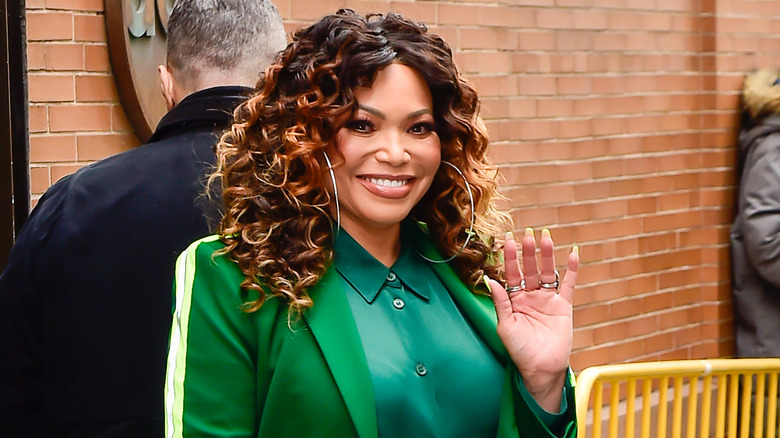 Tisha Campbell smiles and waves at the camera 