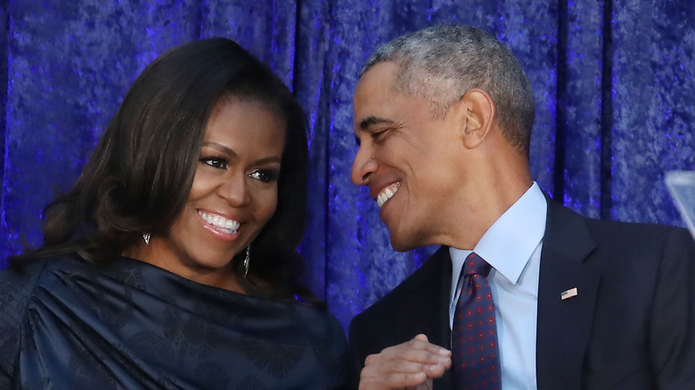 Michelle and Barack Obama smile in 2018