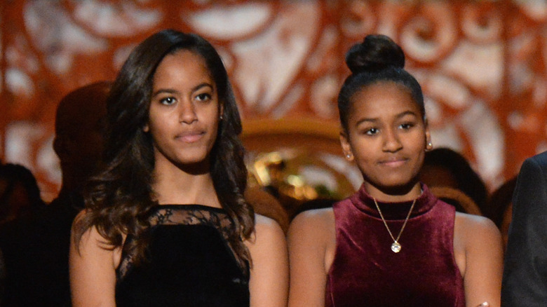 Sasha and Malia Obama, standing next to their dad on a podium