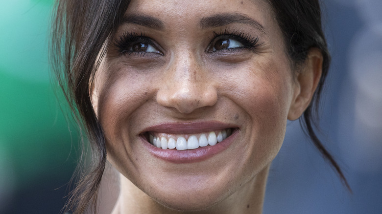 Meghan Markle smiles while looking up