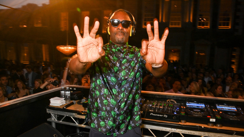 Idris Elba holds up six fingers while DJing