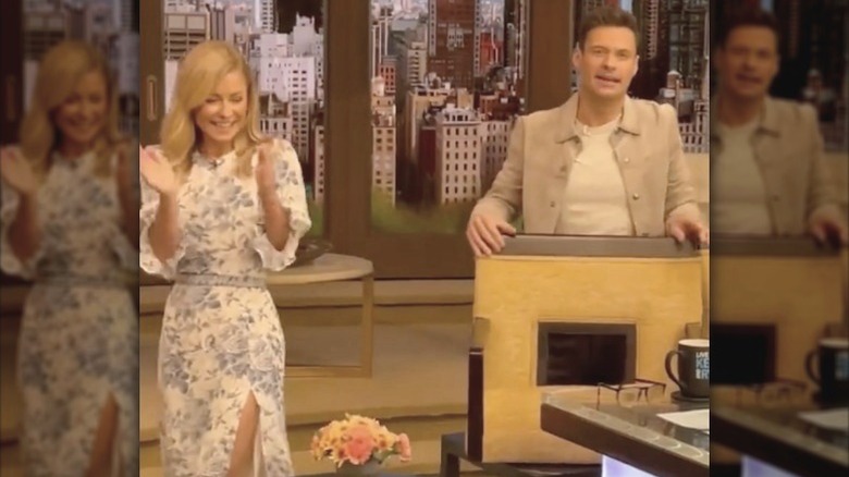 Kelly Ripa clapping beside Ryan Seacrest