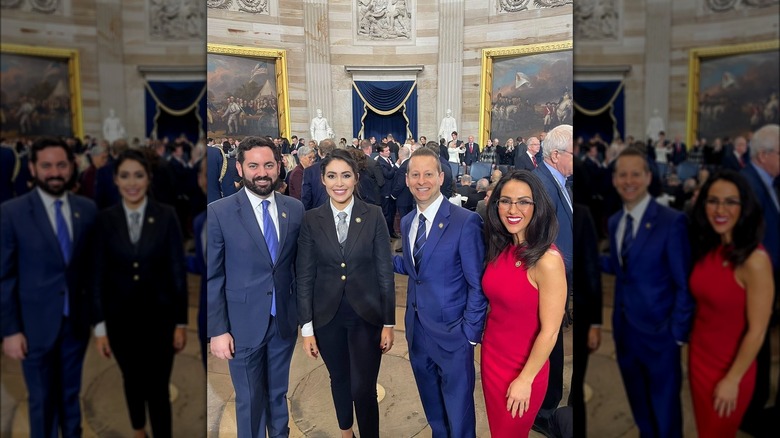 Wearing a bright red dress, Lauren Boebert is all smiles while standing next to her fellow members of congress.