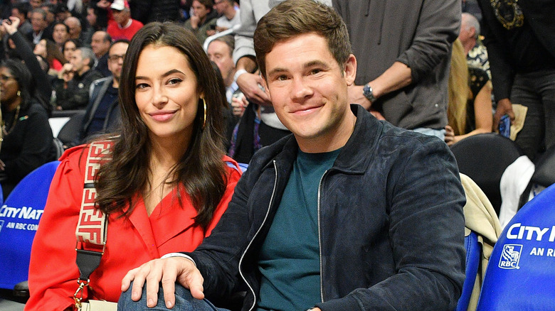 Chloe Bridges and Adam Devine sitting at a sports game