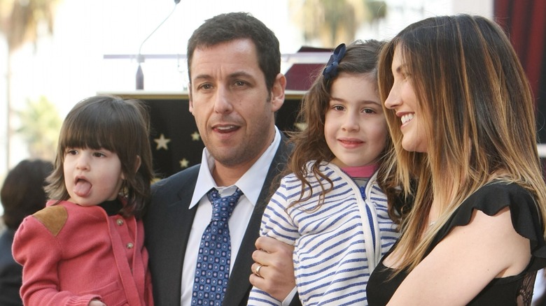 Jackie and Adam Sandler carrying their daughters