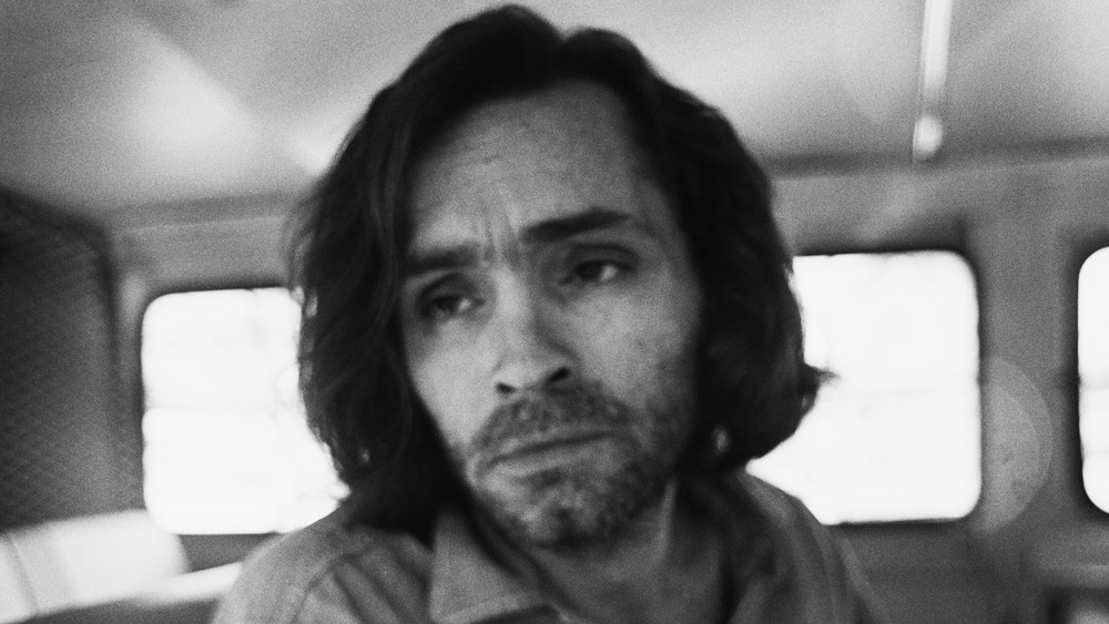 Charles Manson in a police van per black and white image