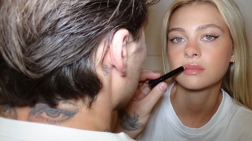 Brooklyn Beckham shows off his eyes tattoo while applying lipstick to Nicola Peltz in an Instagram Selfie 
