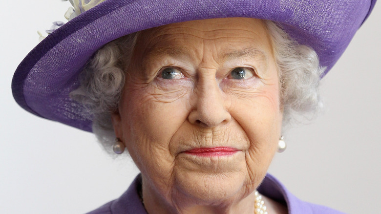 Queen Elizabeth gives slight smile in all lavender outfit and hat