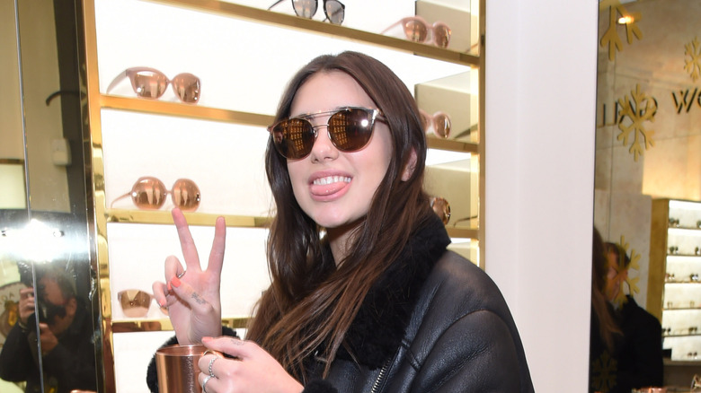 Dua Lipa smiling and throwing up a peace sign