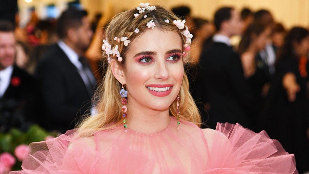 Emma Roberts in a pink dress and flower crown, smiling
