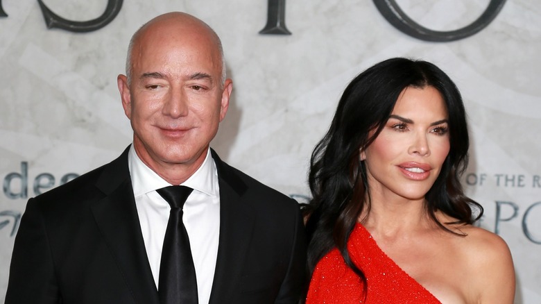 Standing close to each other, Jeff Bezos and Lauren Sanchez look away from the camera.