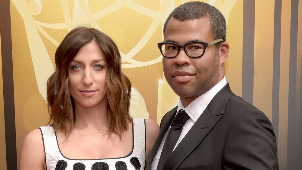 Chelsea Peretti in a white-and-black dress, Jordan Peele in a black suit and glasses