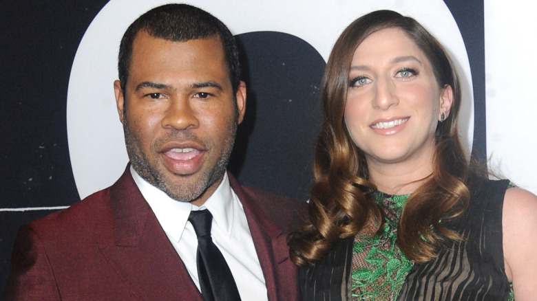Jordan Peele in a maroon suit, Chelsea Peretti in a green-and-black dress