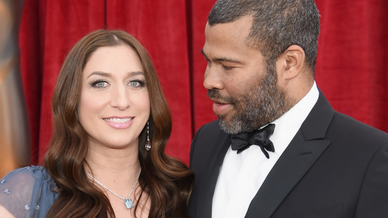 Chelsea Peretti smiling in a blue dress, Jordan Peele in a black suit looking at her