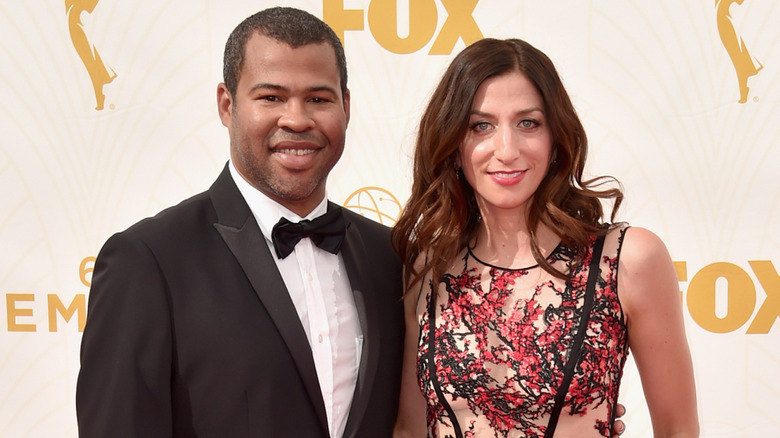 Jordan Peele in a black suit, Chelsea Peretti in a black-and-red dress