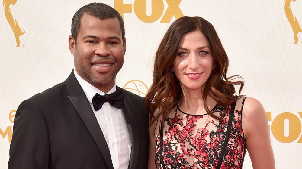 Jordan Peele in a black suit, Chelsea Peretti in a black-and-red dress
