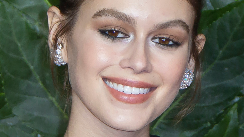 Kaia Gerber smiles wearing a halter dress