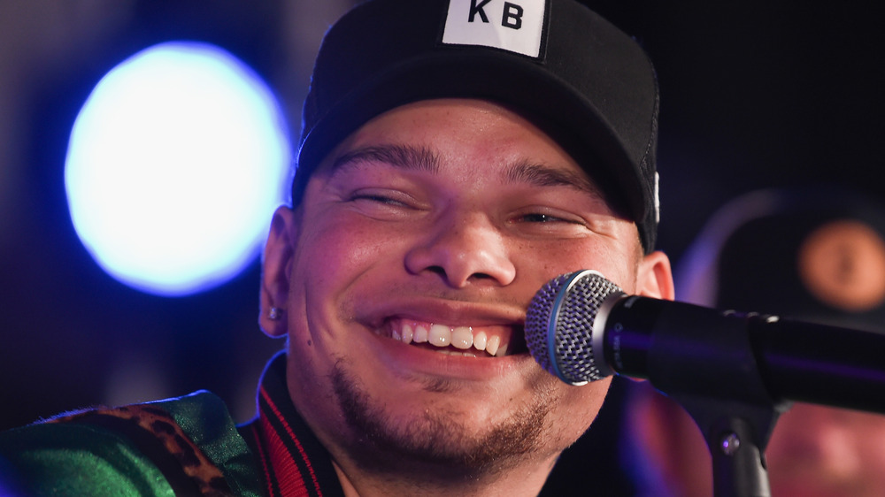 Kane Brown smiling behind microphone