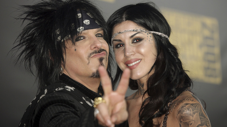 Nikki Sixx making peace sign while hugging Kat Von D