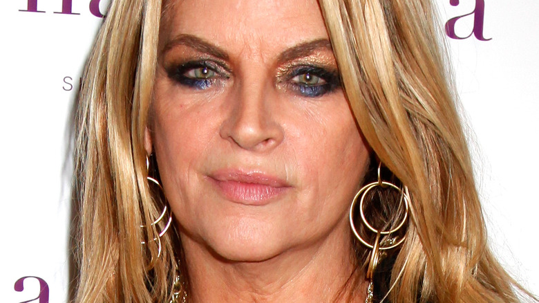 Kirstie Alley wearing hoop earrings and heavy, glitter eye makeup