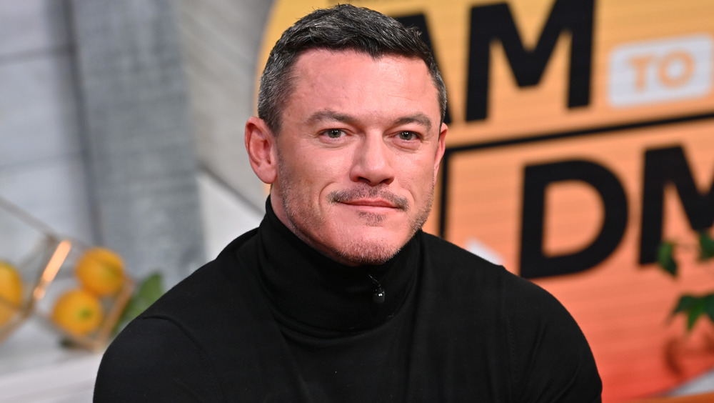 Luke Evans sitting happily at an event