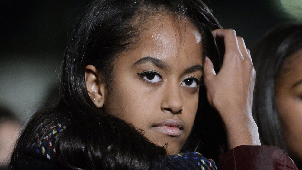 Malia Obama with a neutral expression, fixing her hair