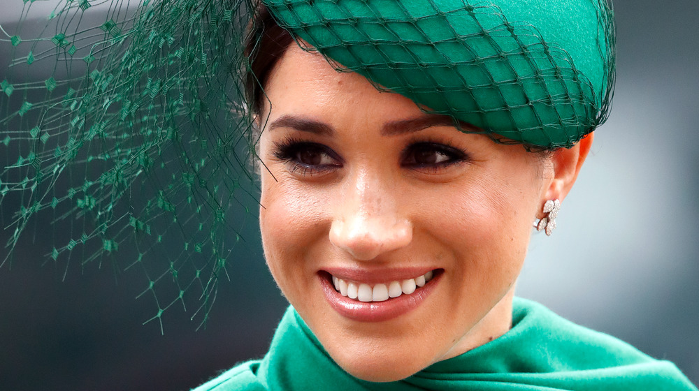 Duchess Meghan Markle smiles in a green hat