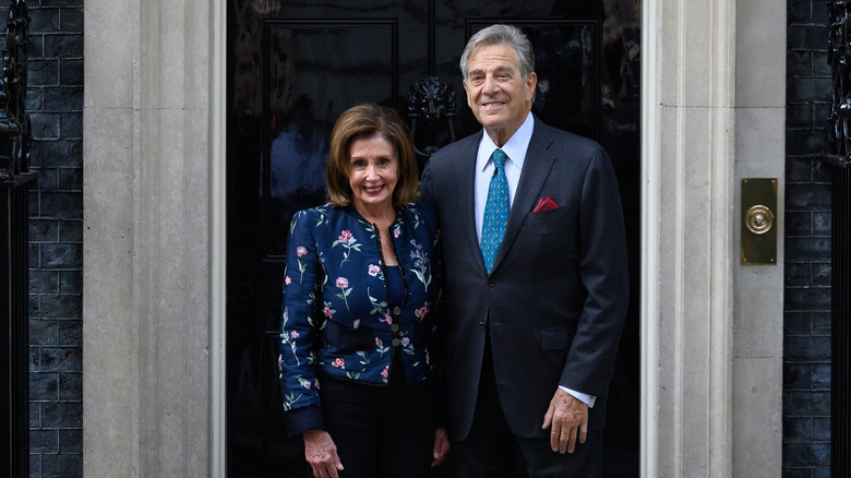 Nancy and Paul Pelosi smiling in front of a door