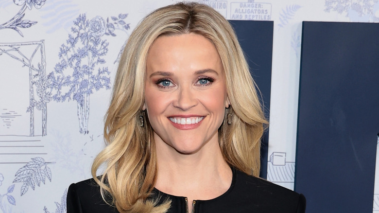Reese Witherspoon wearing a black blazer with gold buttons and zipper