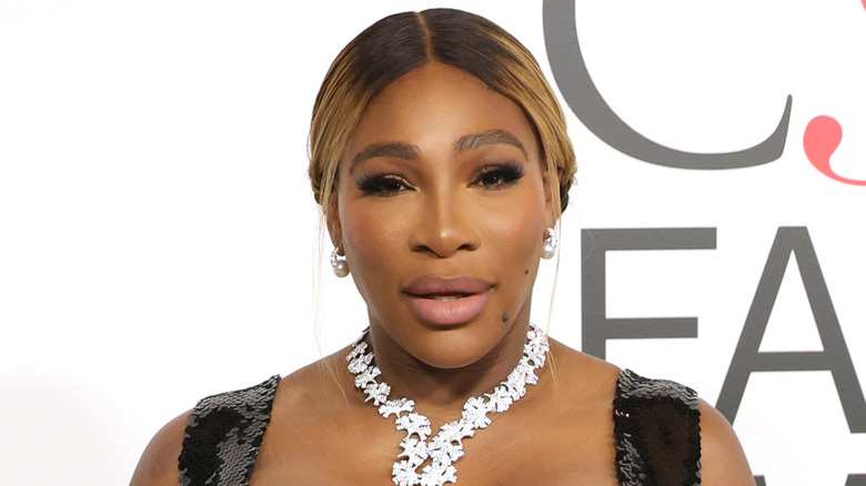 Serena Williams posing on red carpet in silver necklace and black dress