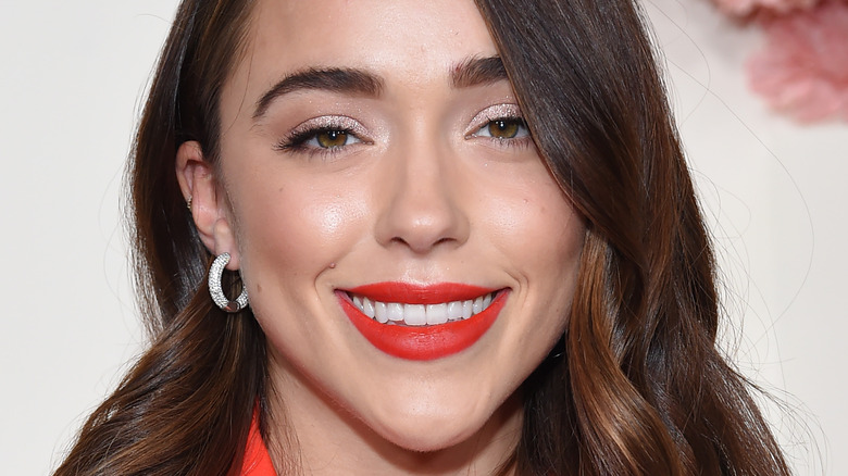 Sophia Culpo wears red-orange lipstick and smiles