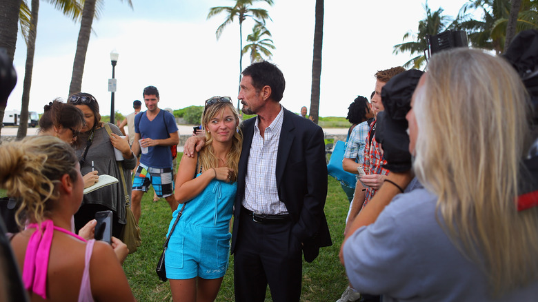 John McAfee with arm around young woman