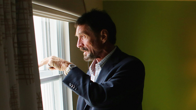 John McAfee peering out of a window