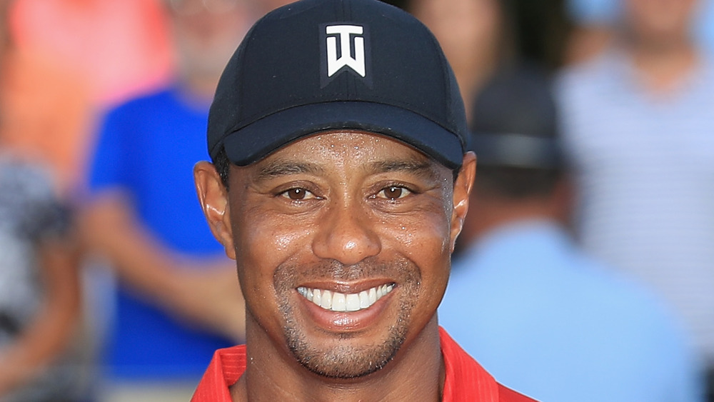 Tiger Woods smiling for photos on the golf course