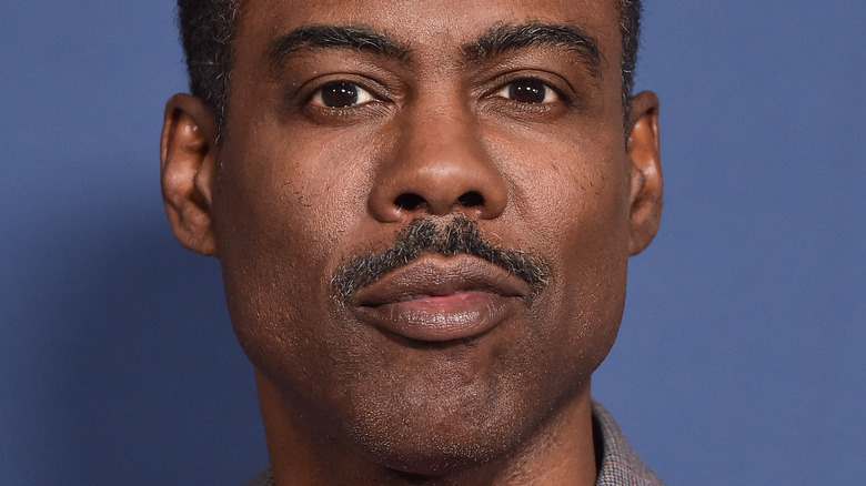 Chris Rock looking serious in front of a blue background