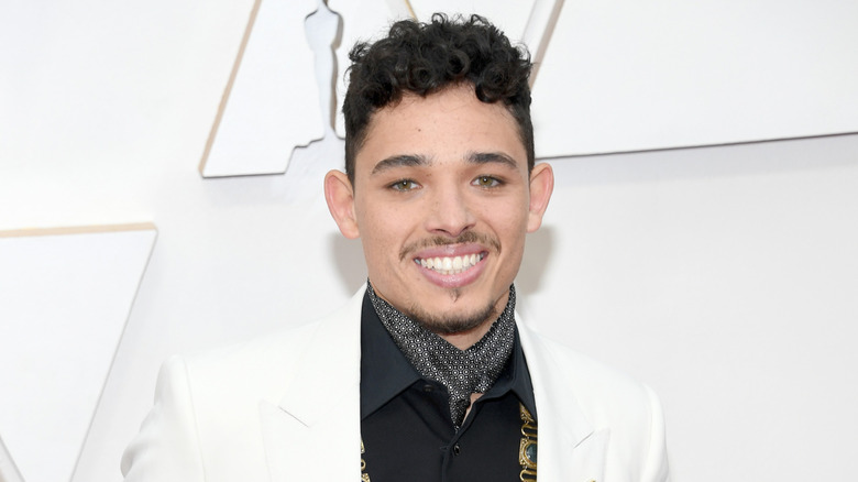 Anthony Ramos smiling in front of white wall
