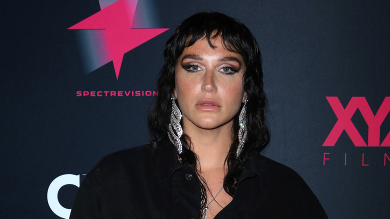Kesha with black hair and big silver earrings