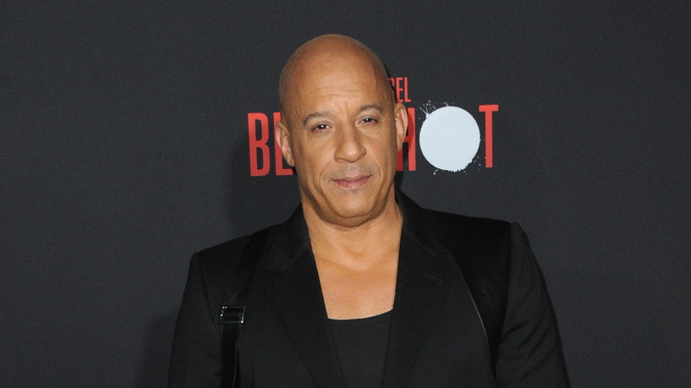 Vin Diesel in an all black ensemble in front of black wall