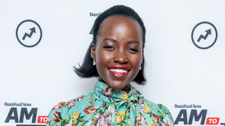 Lupita Nyong'o smiling in a floral dress